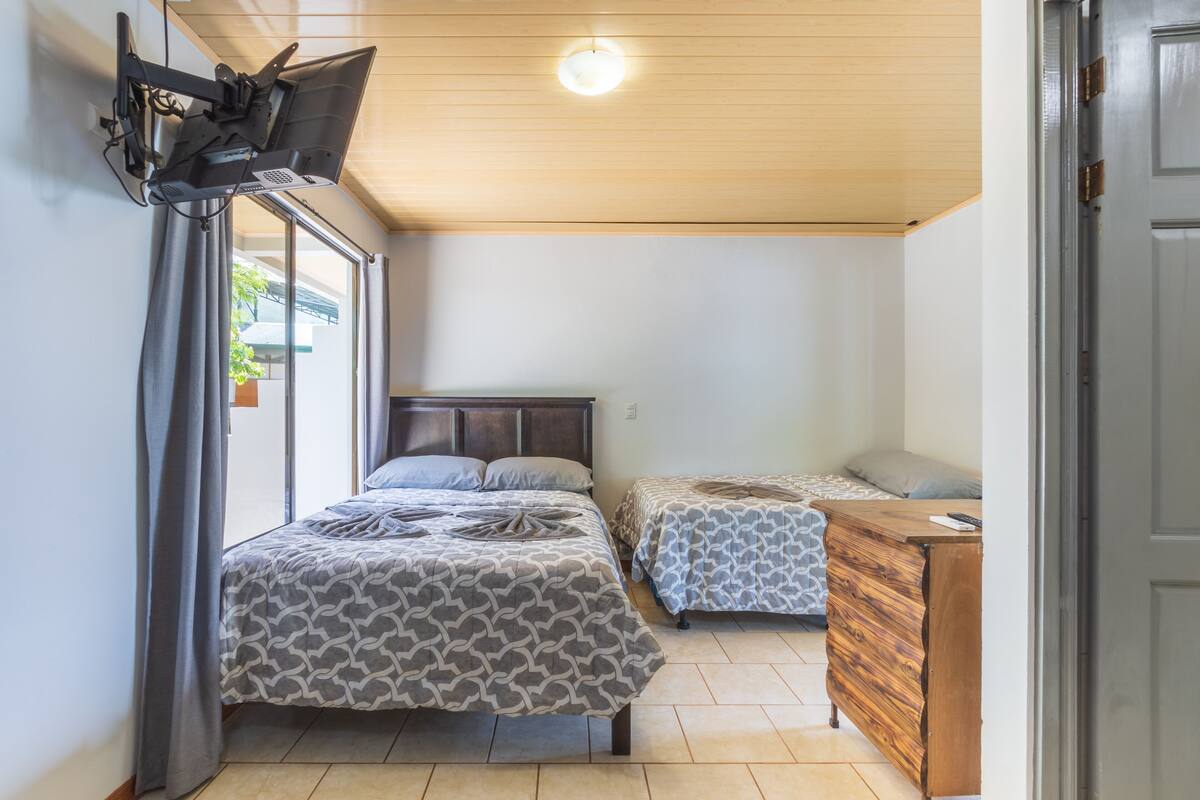 A bedroom with two beds, a wooden dresser, and a ceiling fan.