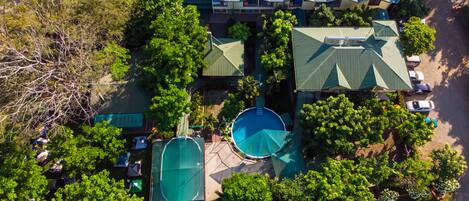 Vista aérea de un resort con varias construcciones, una piscina y follaje circundante.