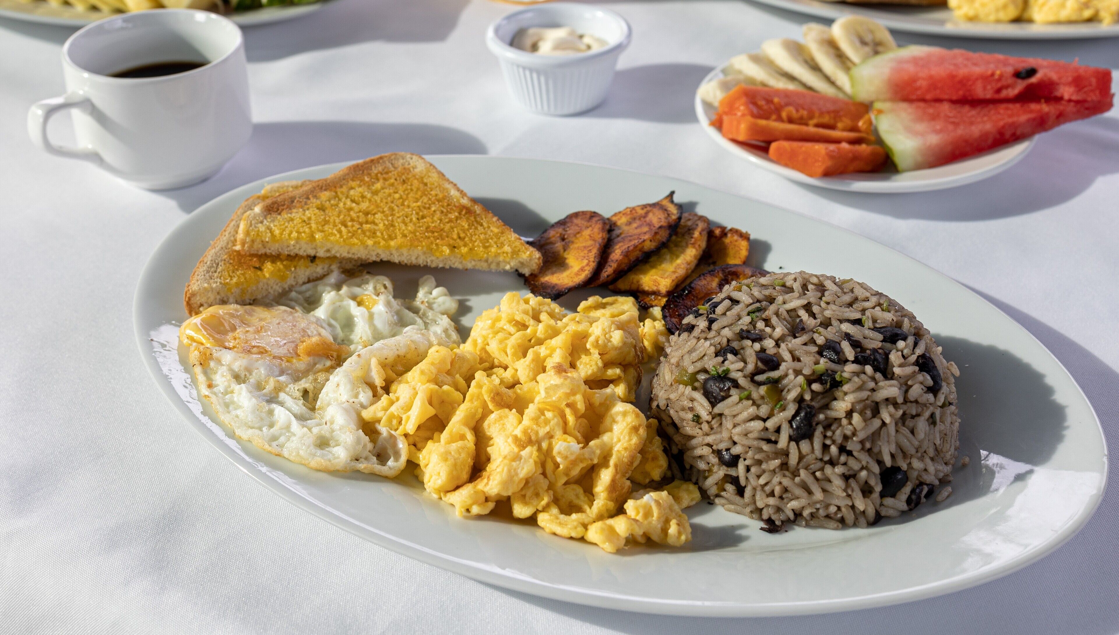 A plate with scrambled eggs, fried rice, toast, and plantains.