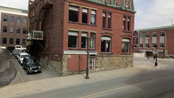A red brick building with a green roof, a fire escape, and a sign for a restaurant.
