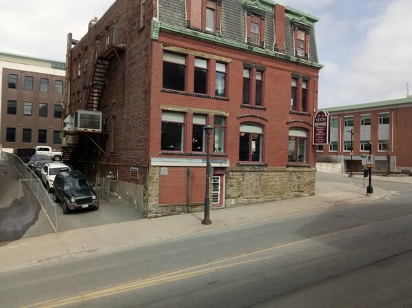 A red brick building with a green roof, a fire escape, and a sign for a restaurant.