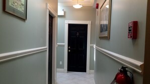 A hallway with a door labeled '3', a fire extinguisher, and a framed picture on the wall. - Chipman Hill Suites on Union (Saint John)