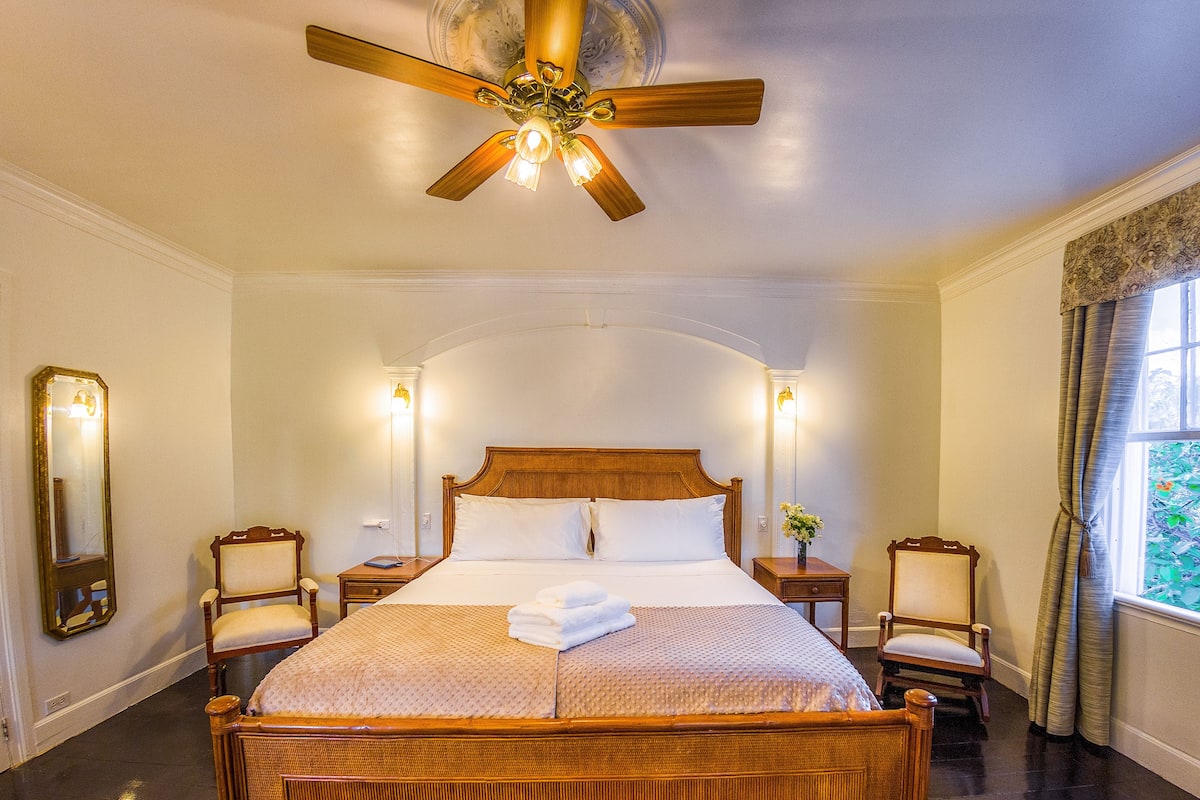 A spacious bedroom with a large bed, a ceiling fan, and two bedside tables with lamps.