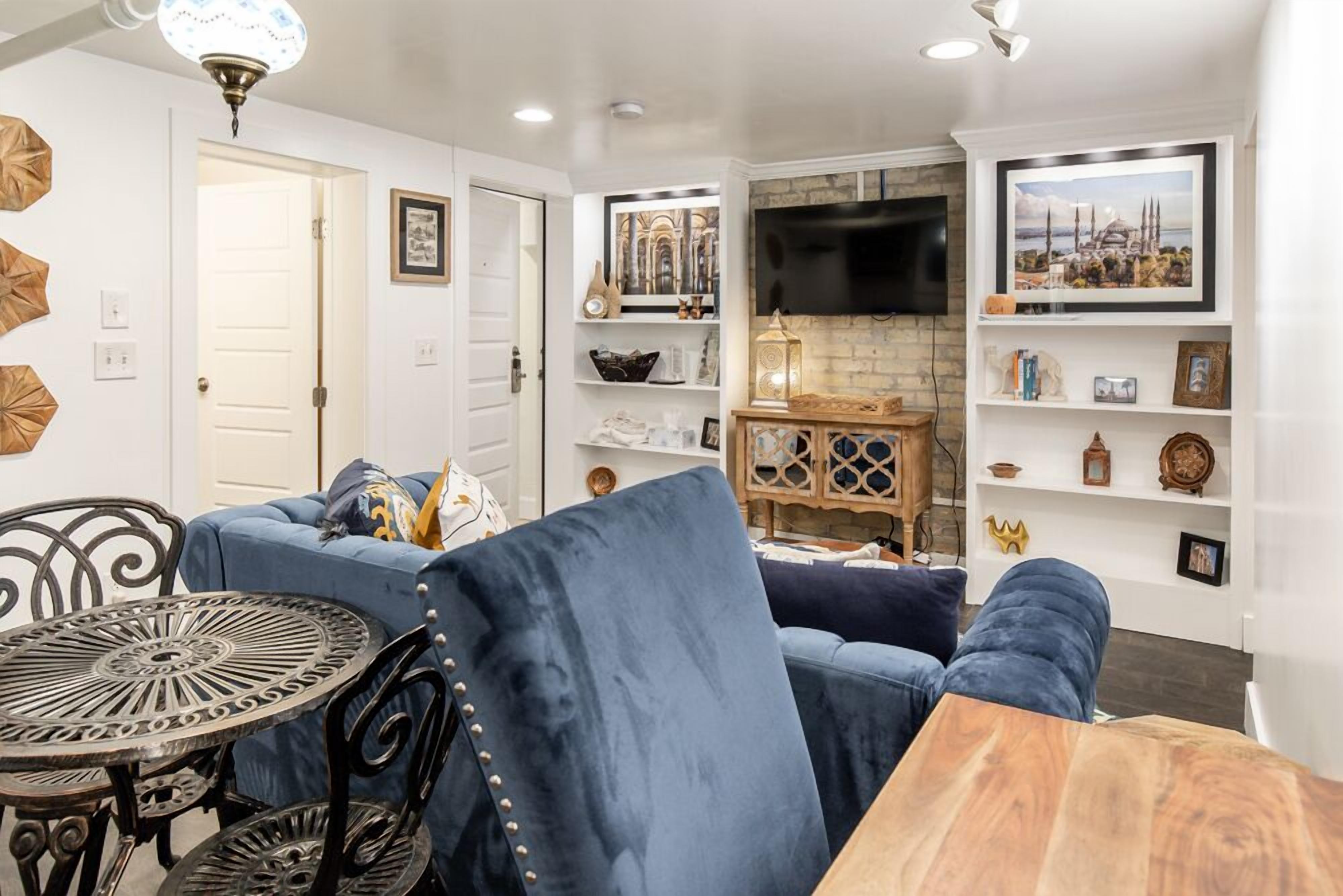 A living room with a blue sofa, a wooden coffee table, and a TV mounted on the wall.