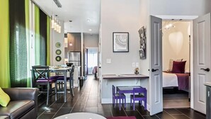 A modern apartment with a dining area, kitchen, and a bedroom with a bed and a heart-shaped wall decoration. - Aspenwood Manor South (Provo)