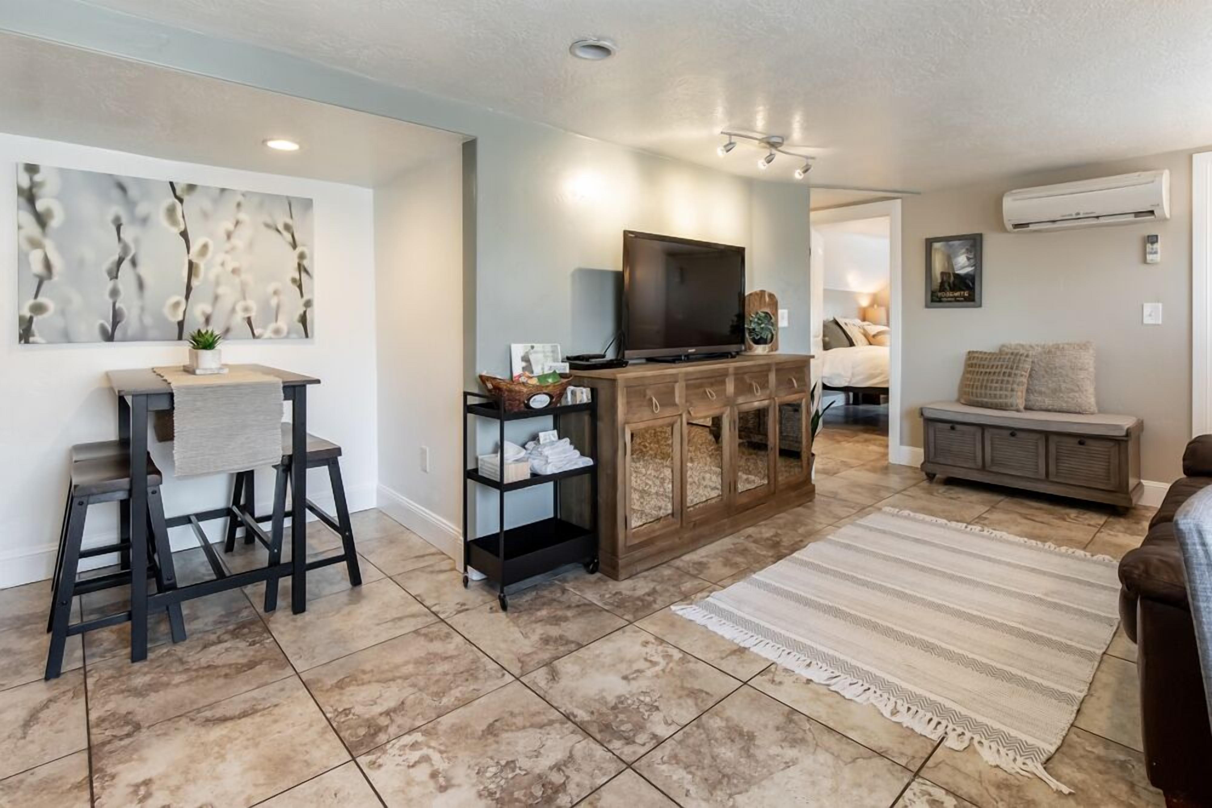 A modern living room with a TV, a wooden cabinet, a sofa, and a dining area with a table and chairs.