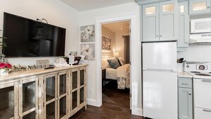 A modern kitchen with a flat-screen TV, wooden cabinets, and a refrigerator. - Aspenwood Manor South (Provo)