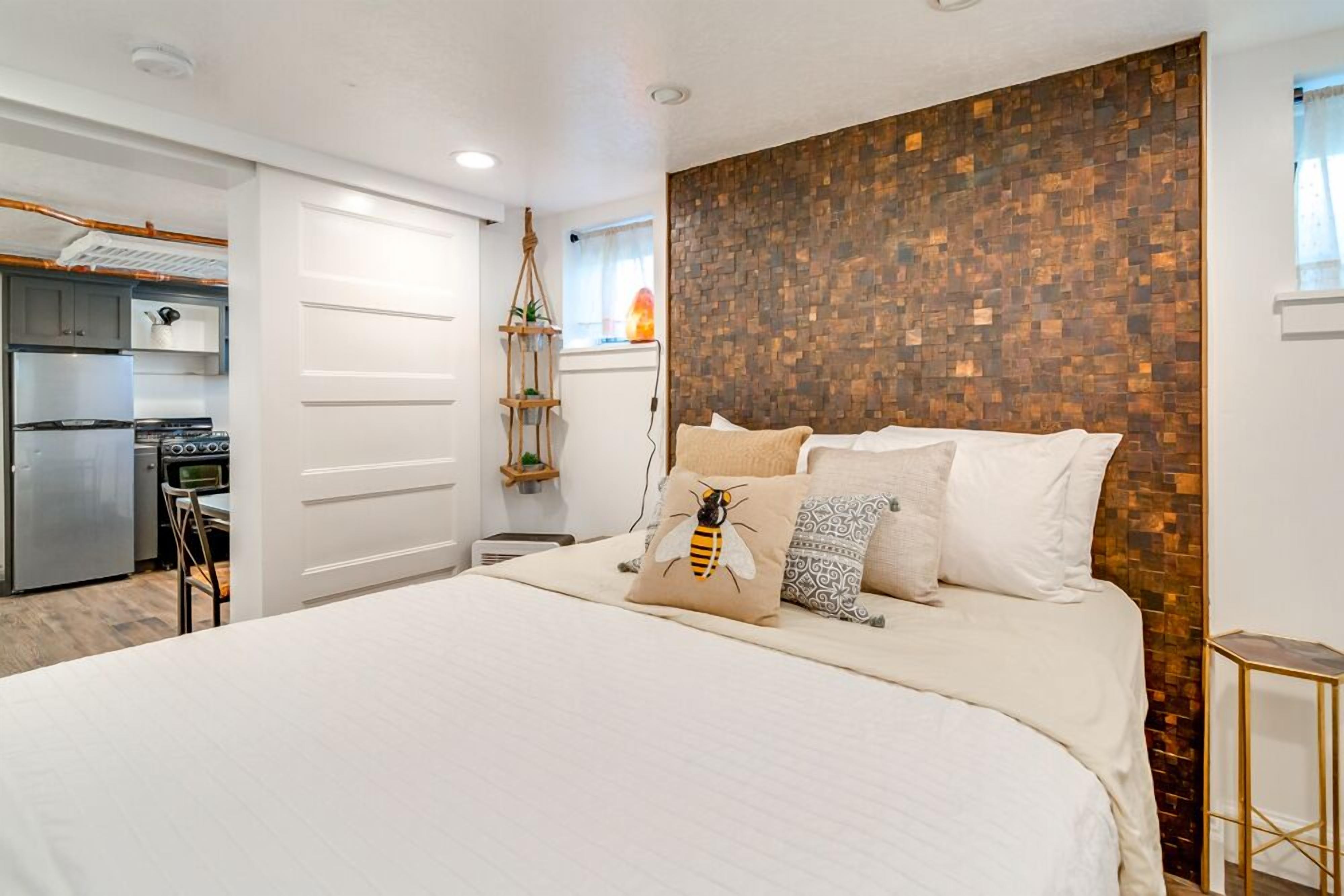 Un dormitorio con una cama grande, una pared de acento de madera y una kitchenette al fondo.
