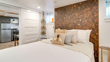Un dormitorio con una cama grande, una pared de acento de madera y una kitchenette al fondo.