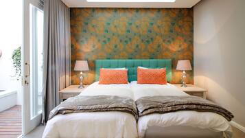 A double bed with two pillows, a teal headboard, and a patterned wall.