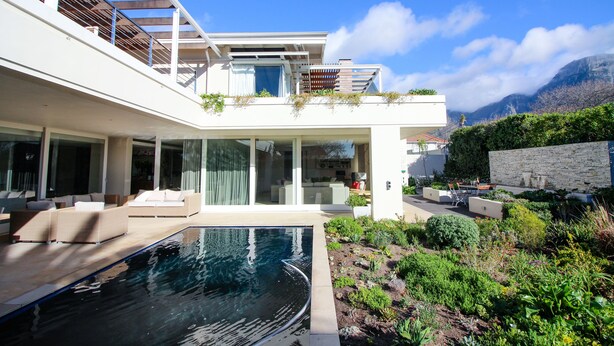 Uma casa moderna com piscina, área de estar externa e vista para montanhas.