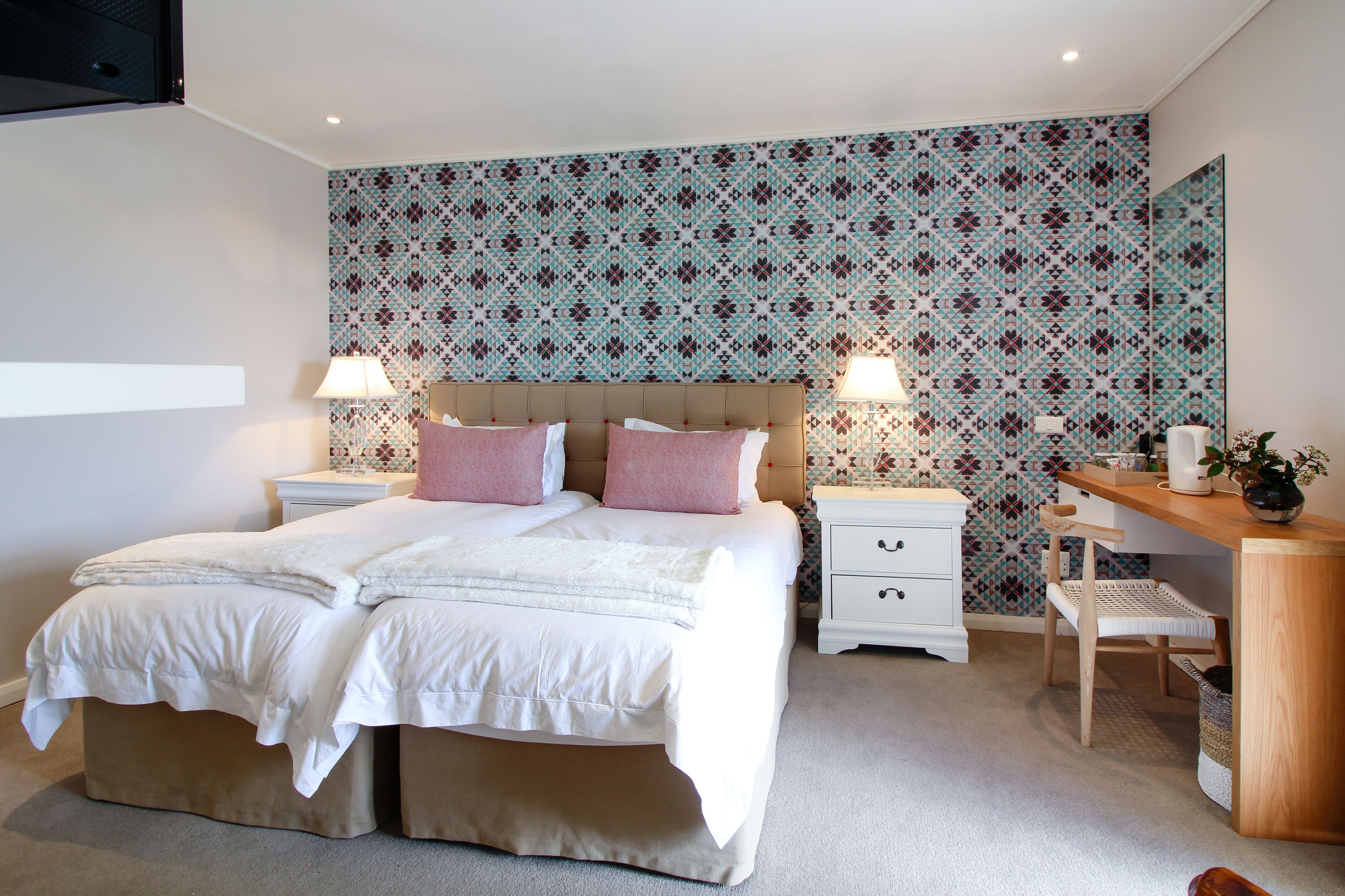 Ein Schlafzimmer mit einem großen Bett, zwei Nachttischen, einem Schreibtisch und einem Sessel.