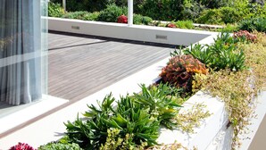 Um edifício moderno com um jardim no terraço, apresentando diversas plantas e uma estrutura de pérgula.