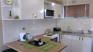 Cozinha compacta com armários brancos, micro-ondas, torradeira e pia.