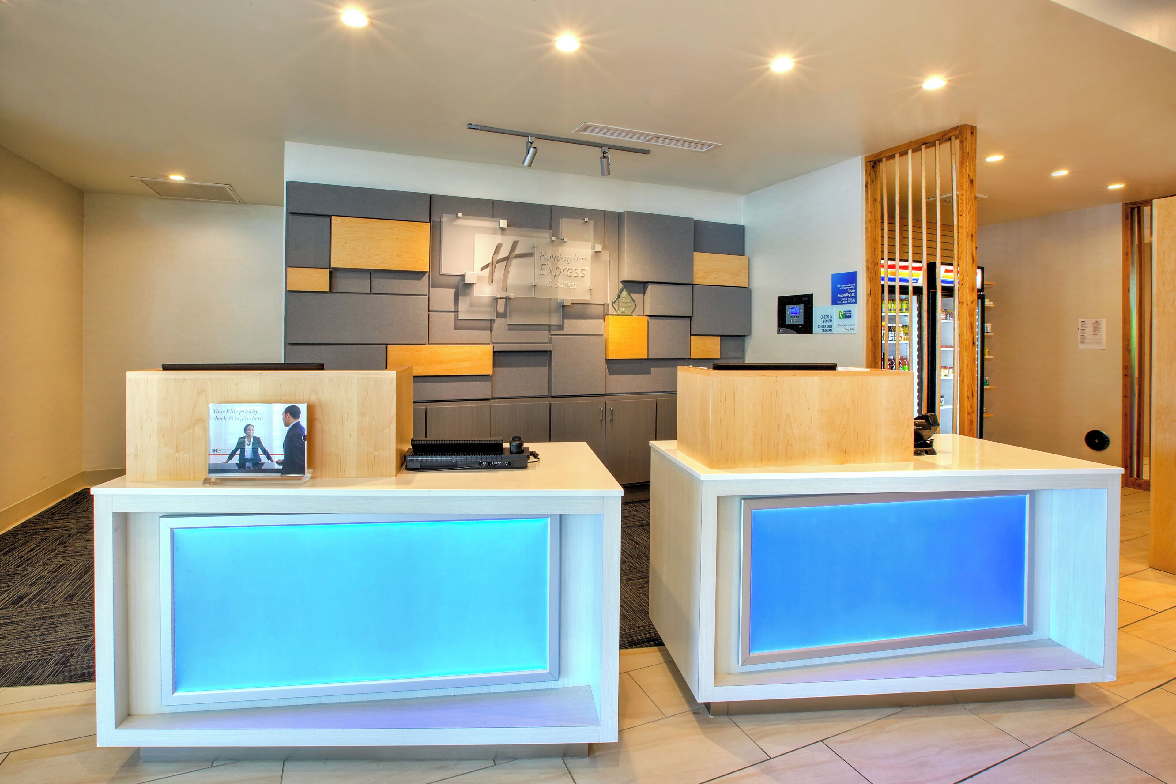 A hotel reception area with two reception desks, a wall-mounted sign, and a check-in counter.