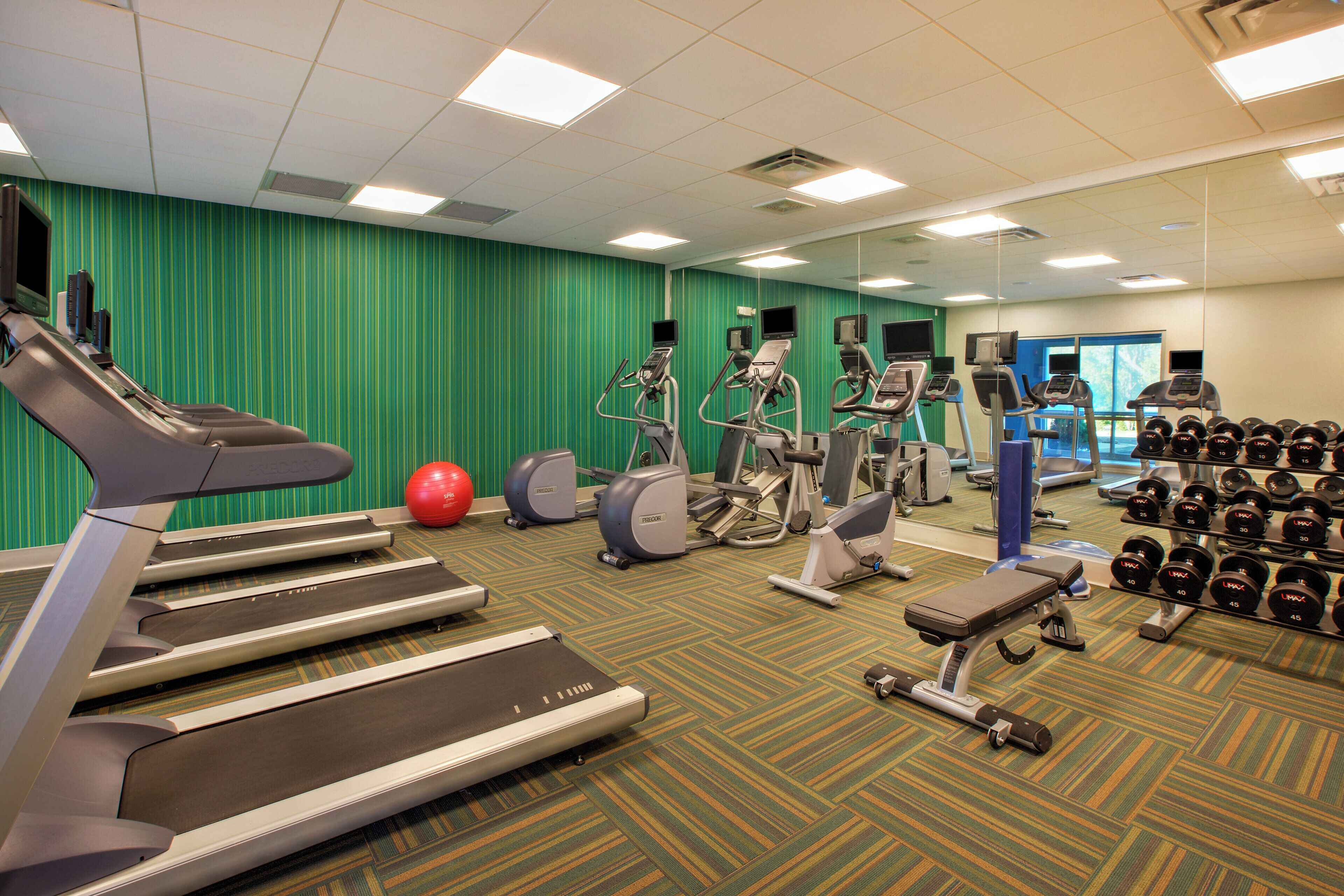 Een sportschool met loopbanden, elliptische trainers en losse gewichten.