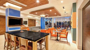 A modern interior with a black table, wooden chairs, and orange seating.