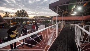 Uma varanda com grade, uma mesa e cadeiras.