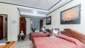 Quarto de hotel com duas camas, uma cabeceira de madeira, um quadro e um ventilador de teto.