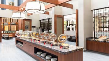 A buffet area with various food stations, a seating area with chairs, and a large window providing natural light.