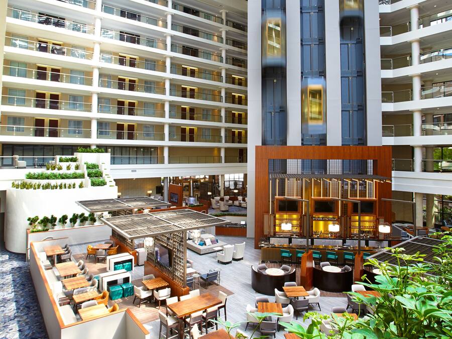 A multi-level hotel lobby with a central bar area, seating arrangements, and a view of the upper floors.