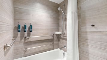 A modern bathroom with a bathtub, grab bars, and a shower with a handheld showerhead.