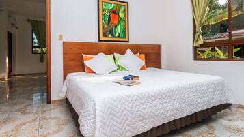 A hotel room with a bed, a painting on the wall, and a window with curtains.