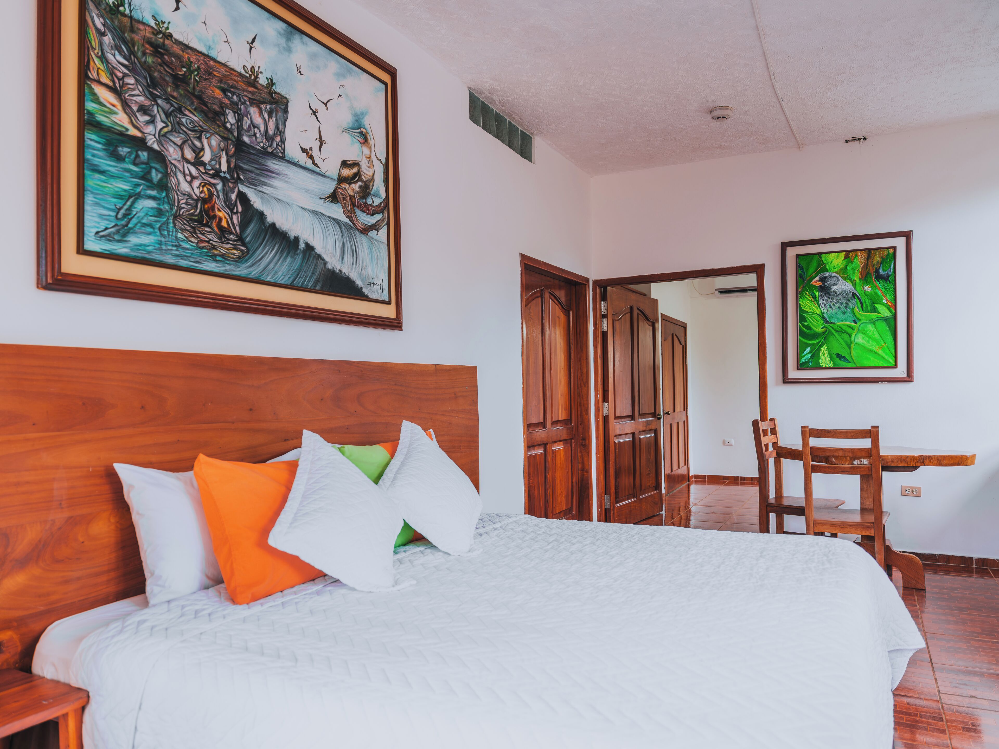 A hotel room with a wooden headboard, a bed with white bedding, a green pillow, and a painting of a bird on the wall.