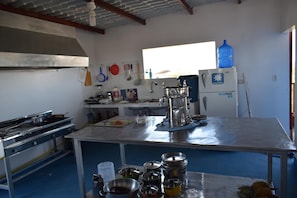 Une cuisine équipée d’appareils électroménagers en acier inoxydable, d’un grand distributeur d’eau et de divers ustensiles de cuisine.