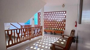 Ein geräumiges Zimmer mit einem Holzespeisetisch und -stühlen, einem dekorativen Holzverkleidungselement und Blick auf ein Gebäude.