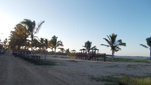 Ein Strand mit einem Feldweg, Palmen und einer Spielgerüst.