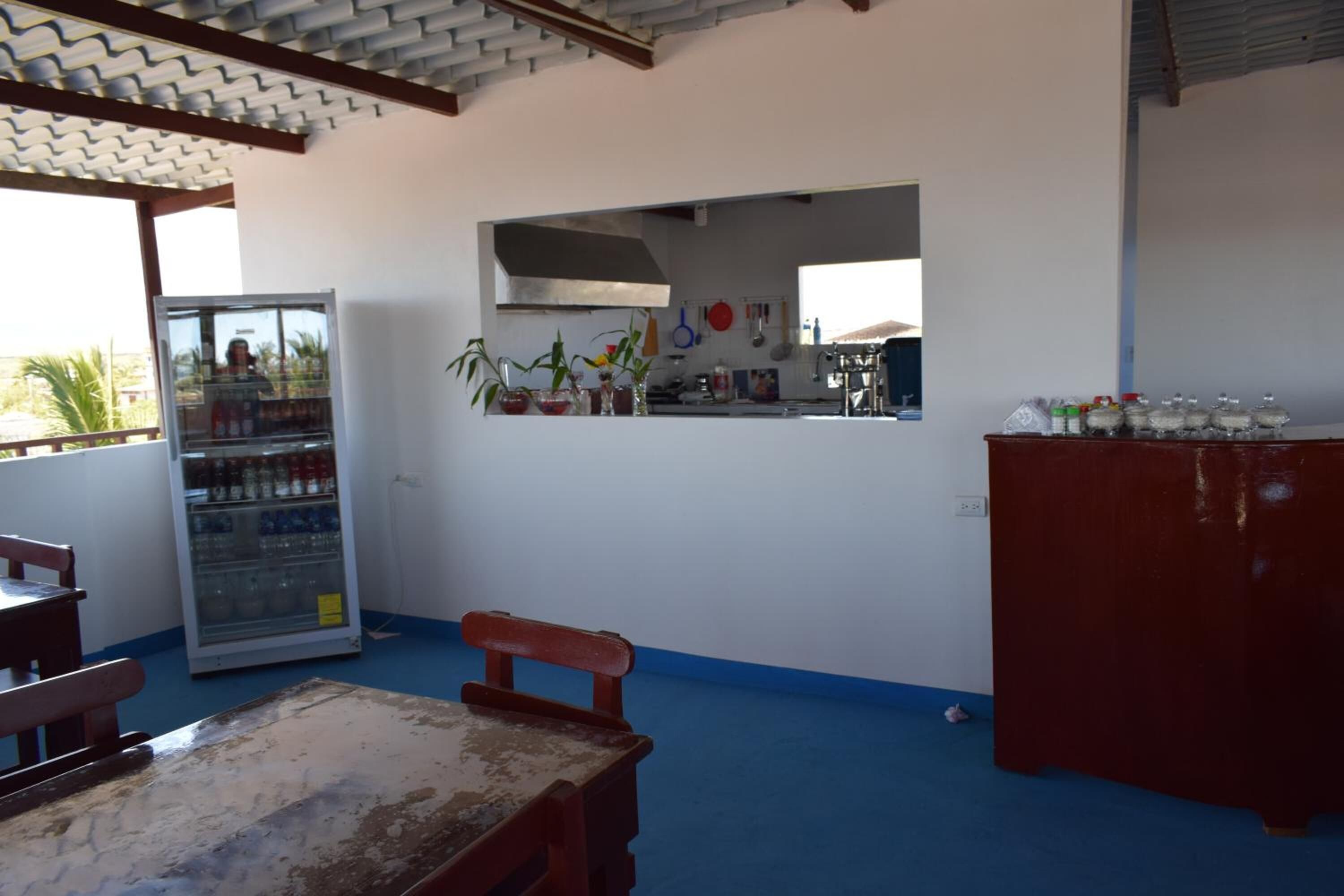A kitchen area with a refrigerator, a wooden table, and a bench.