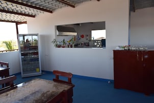 Una cocina con refrigerador, una mesa de madera y un banco.