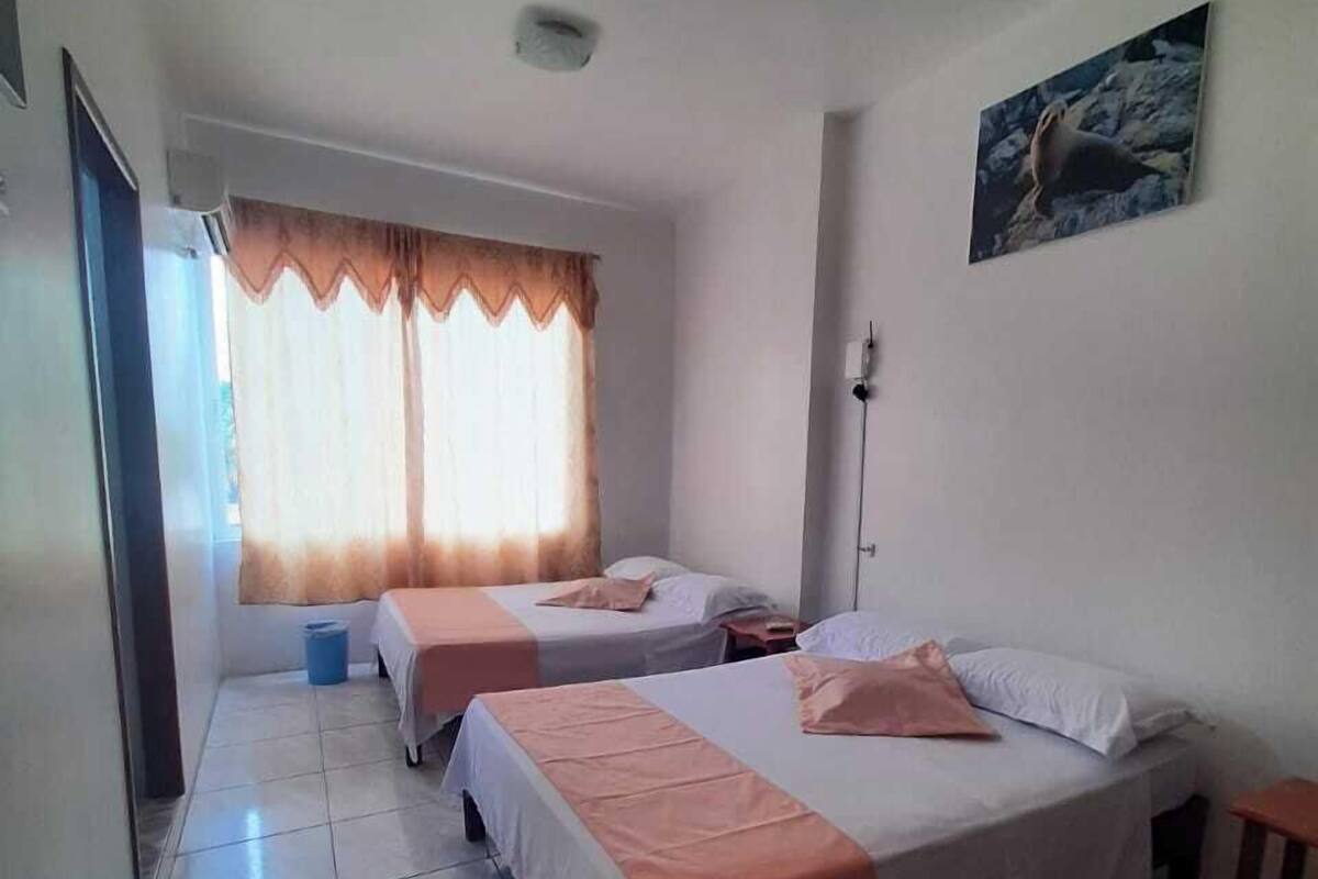 A hotel room with two beds, a window with curtains, a painting on the wall, and a tiled floor.