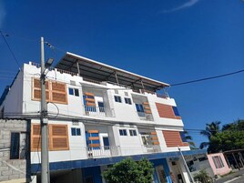 Un edificio de dos plantas con techo plano, varios balcones y una combinación de estilos de ventanas.