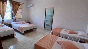 Ein Hotelzimmer mit vier Einzelbetten, einem großen Spiegel und einem fenster mit Vorhängen.