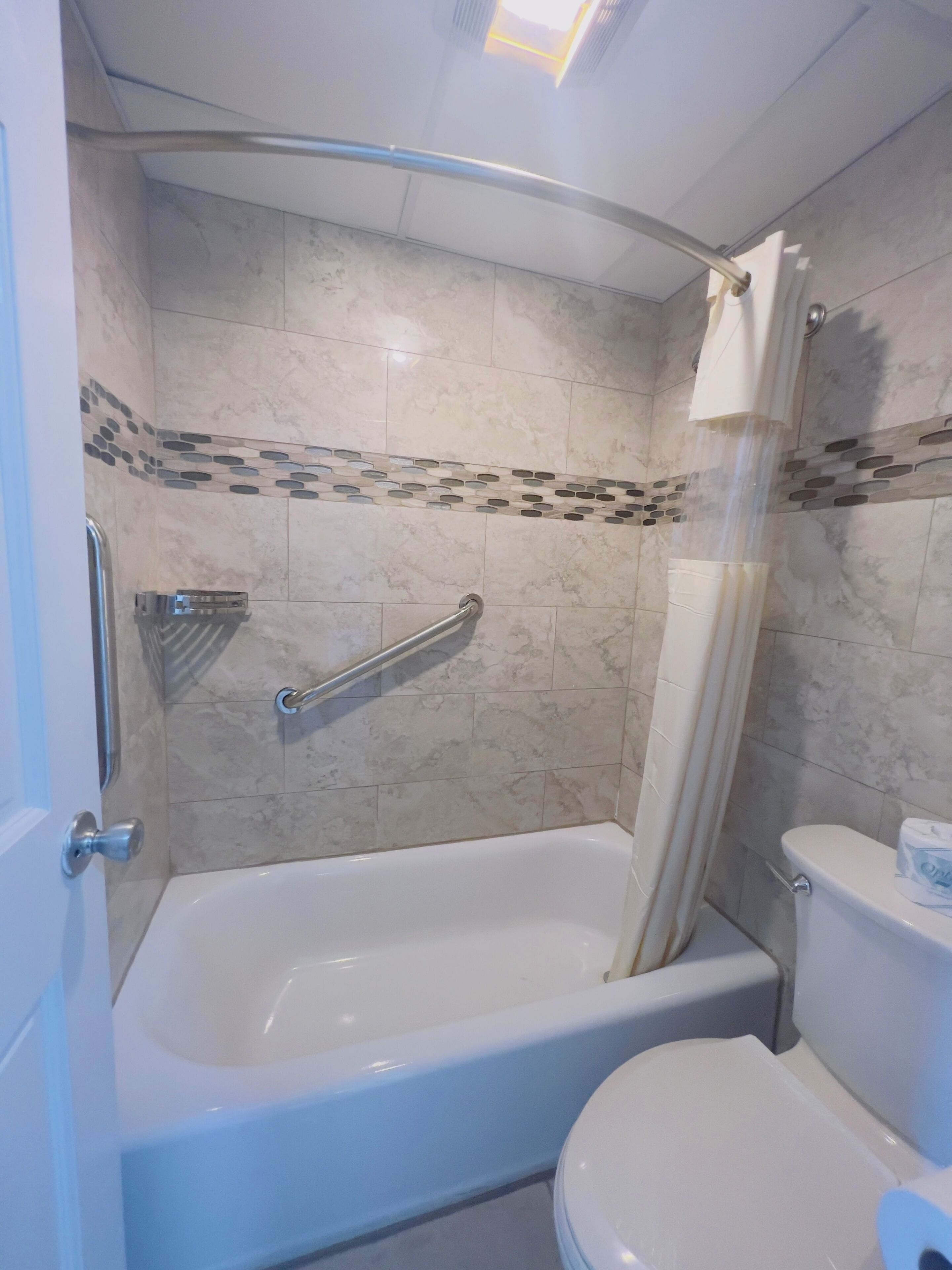A bathroom with a bathtub, toilet, and shower curtain.