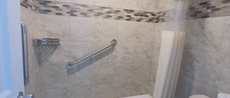A bathroom with a bathtub, toilet, and shower curtain.
