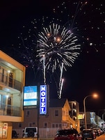 Un motel con letrero, balcón y estacionamiento.