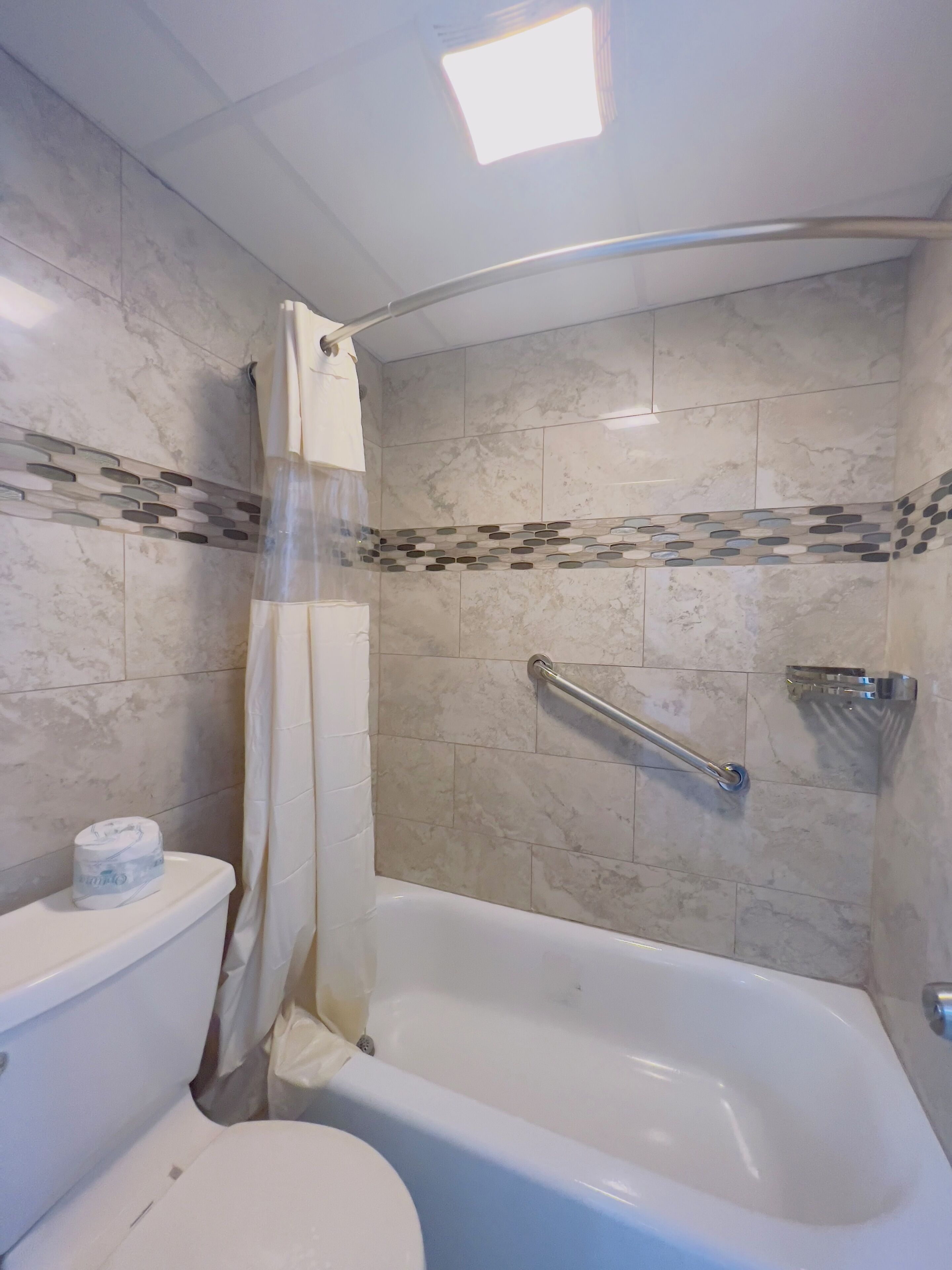 Un baño con bañera, inodoro y cortina de ducha.
