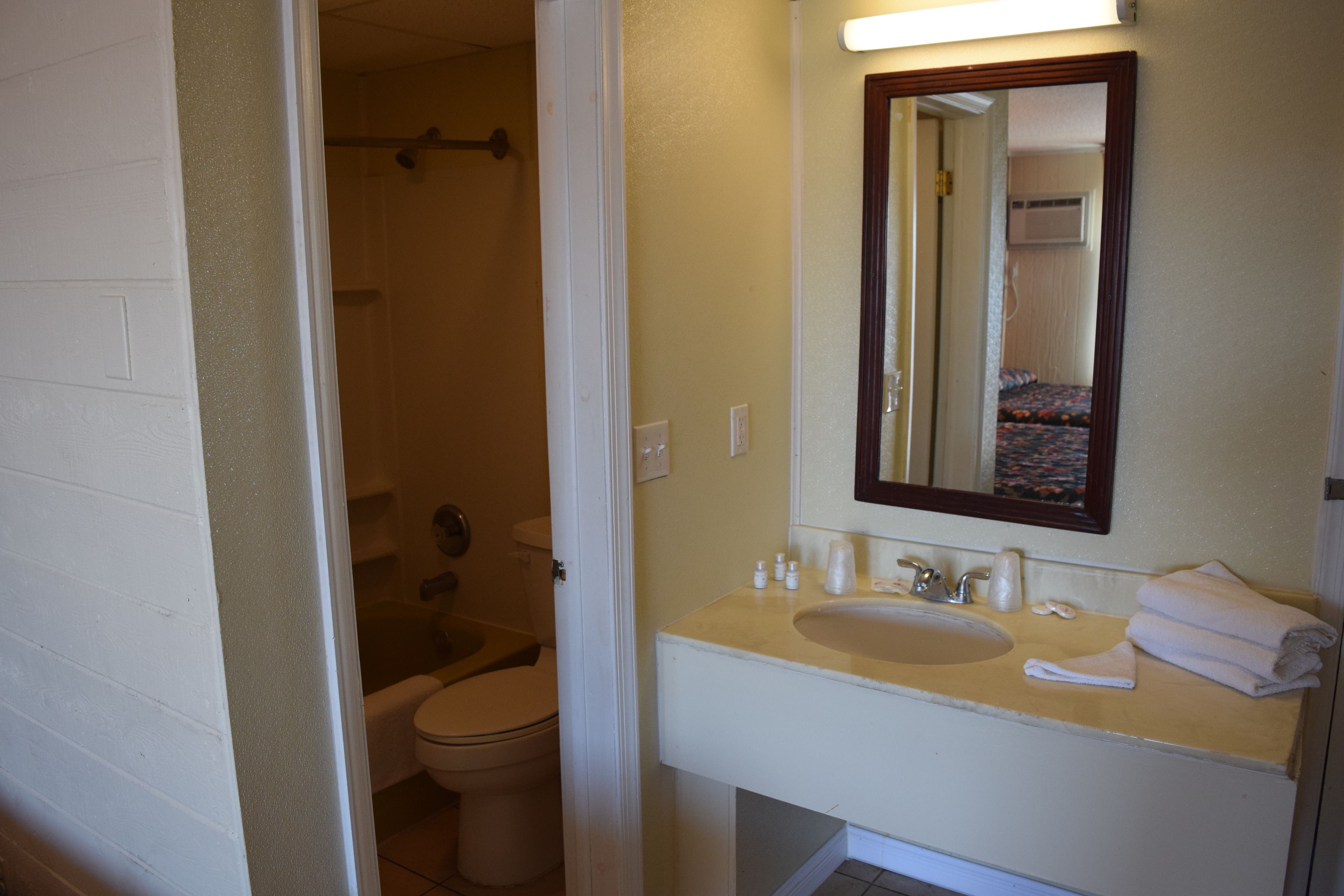 A bathroom with a white sink, mirror, and toilet.