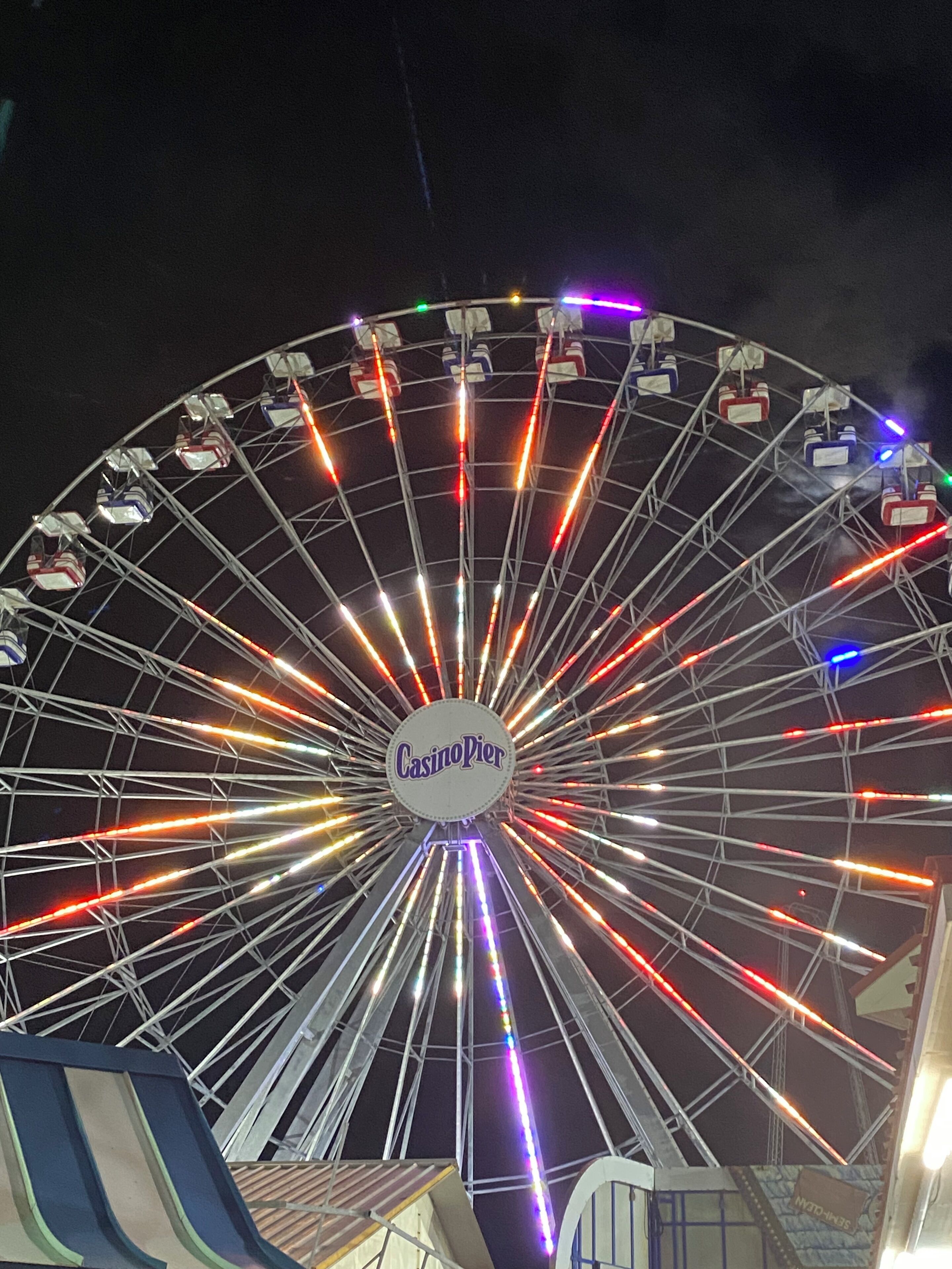 A Ferris wheel with the Casino Pier logo, surrounded by a metal framework and illuminated lights.