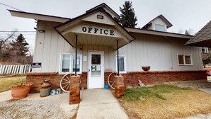 A building labeled "OFFICE" with a front entrance, a brick base, and a small porch area. - Trails End Motel (Lewistown)