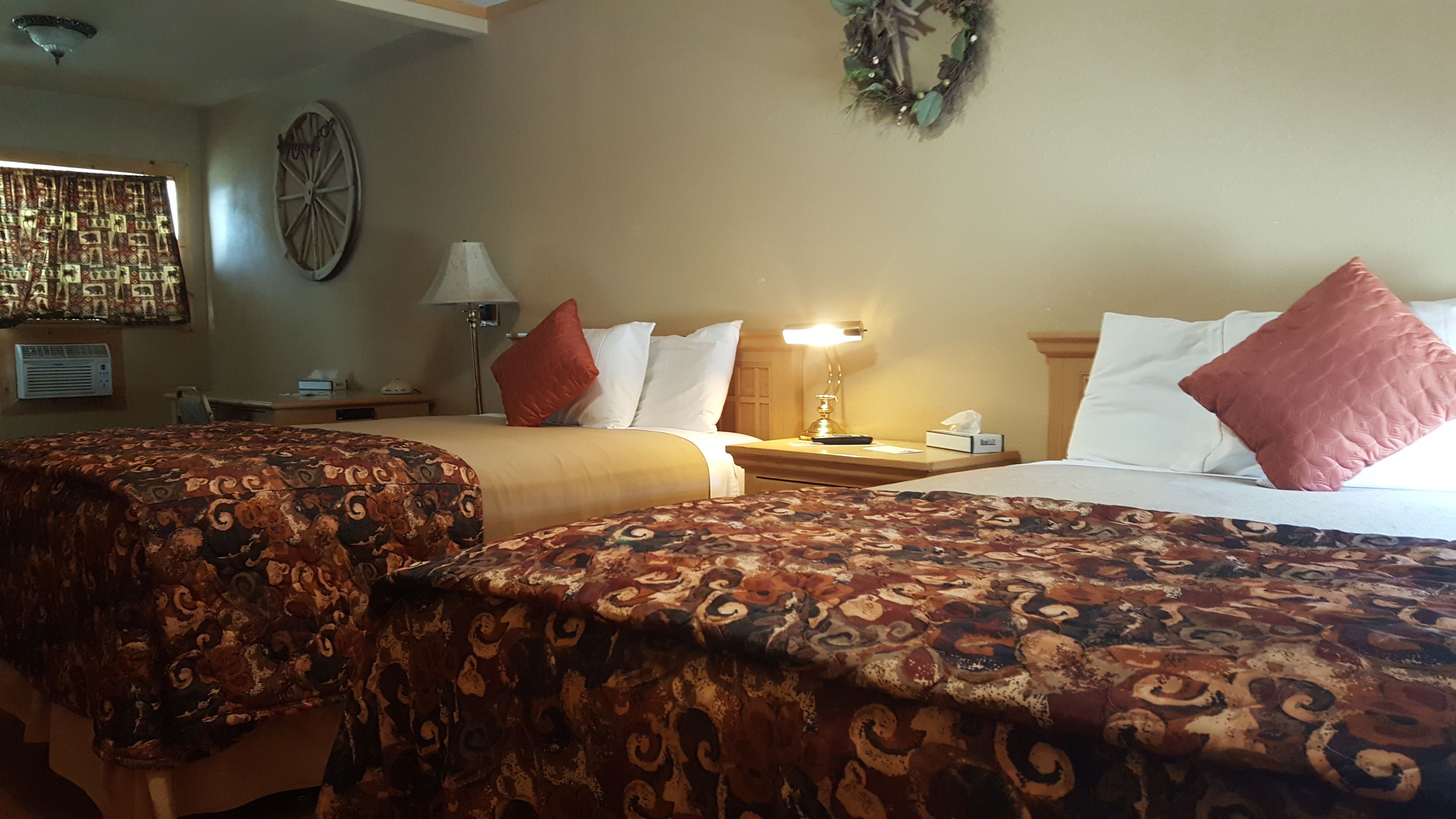 Habitación de hotel con dos camas, una lámpara, un reloj, un adorno en la pared y una ventana con cortinas.