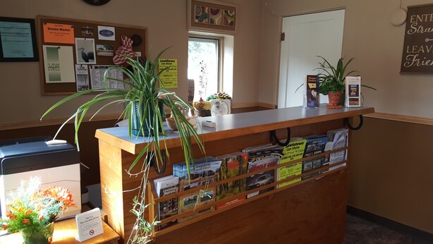 A reception desk with a plant, magazines, and a sign indicating a smoking area. - Trails End Motel (Lewistown)