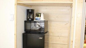 A compact kitchenette with a black refrigerator, a microwave, and a coffee maker on top. - Trails End Motel (Lewistown)