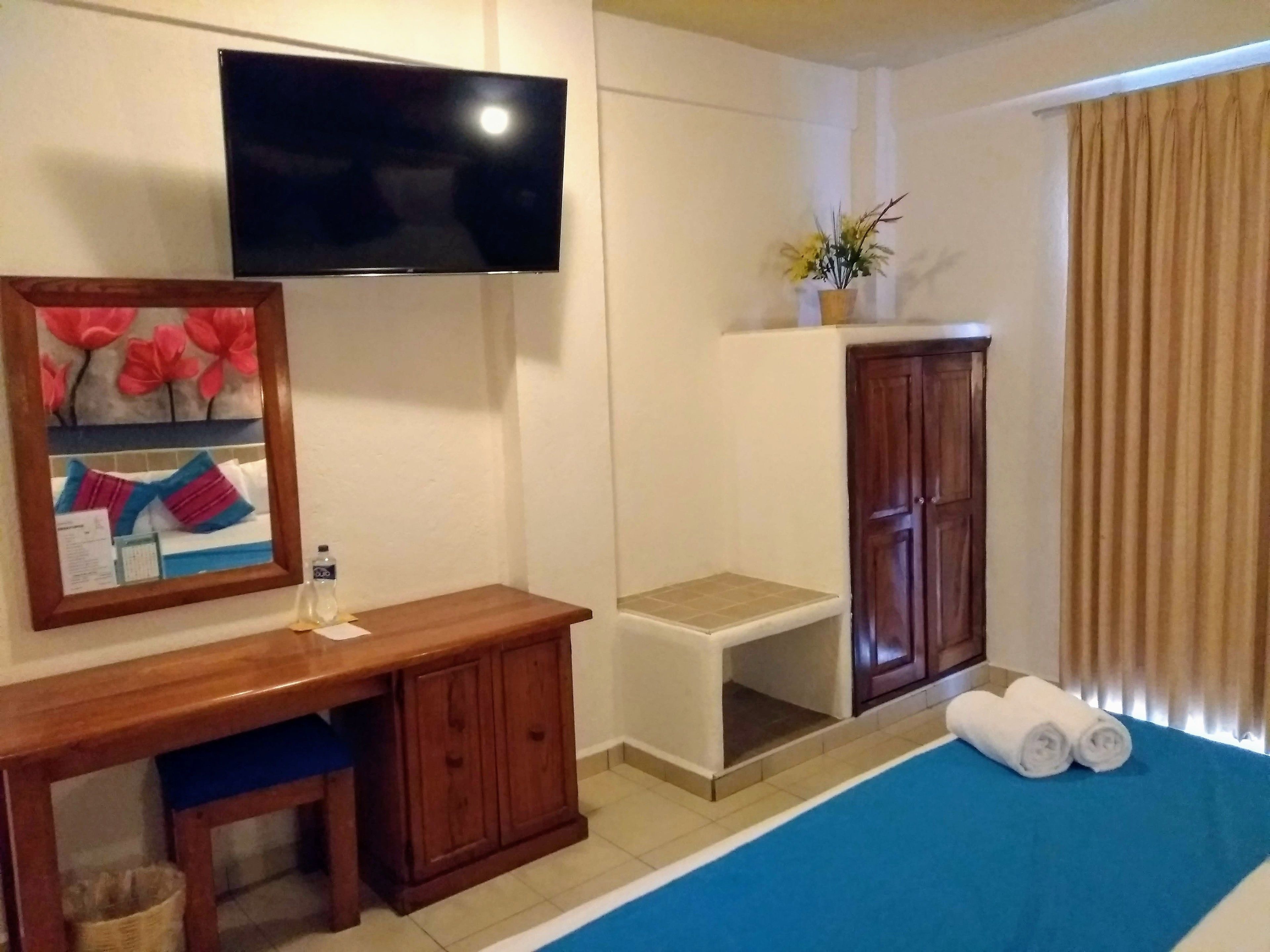 Une chambre d’hôtel comprenant un lit, un bureau, une télévision, une armoire et une petite table.