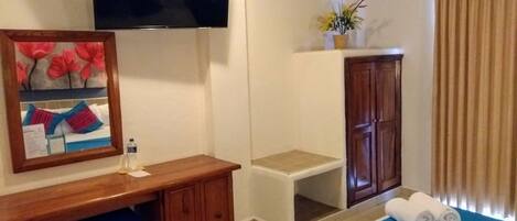 Une chambre d’hôtel comprenant un lit, un bureau, une télévision, une armoire et une petite table.