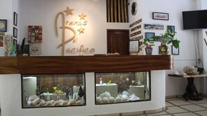 Zona de recepción con mostrador de madera, cuadros enmarcados y un letrero en la pared.
