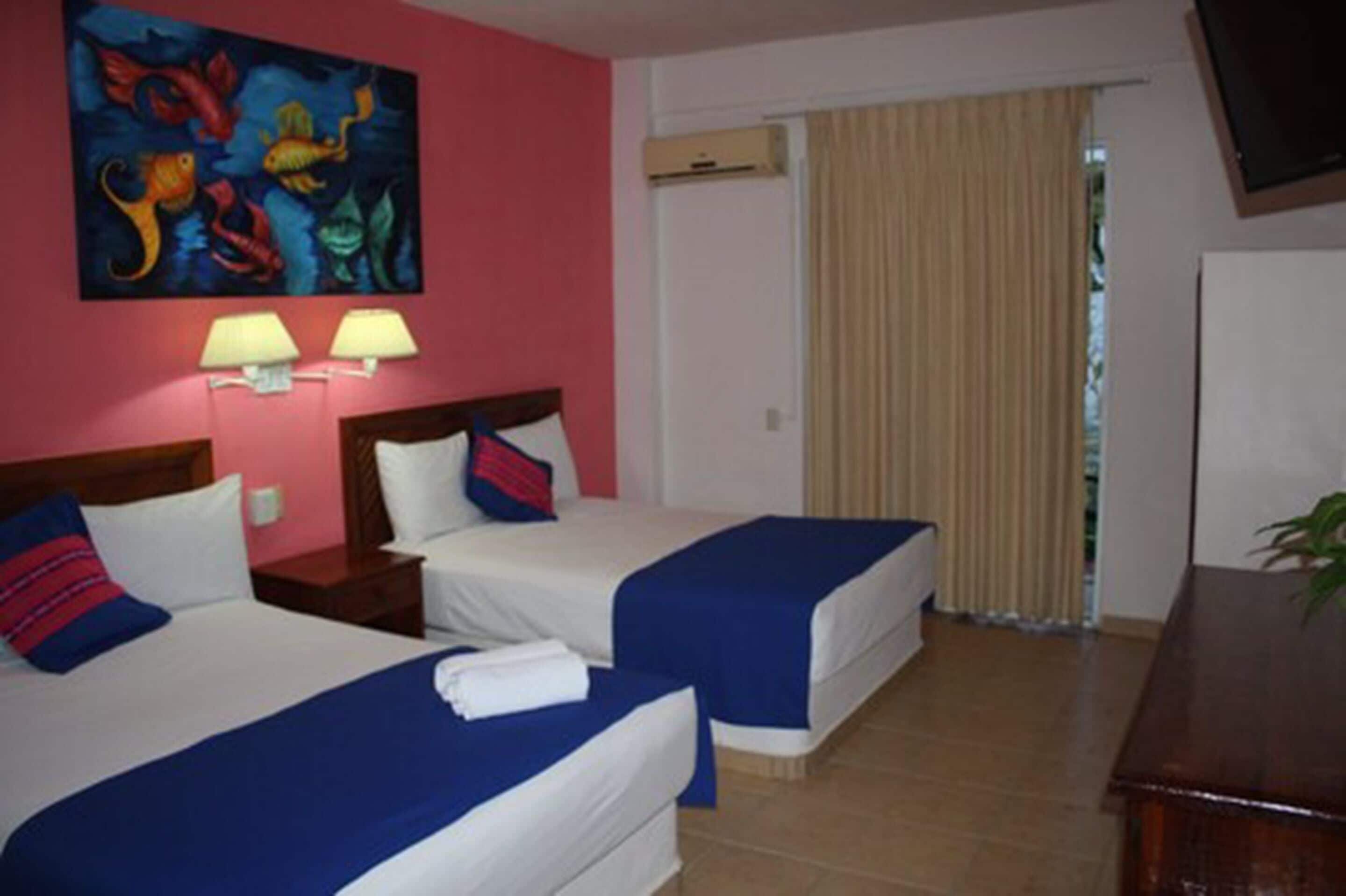 Ein Hotelzimmer mit zwei Betten, einem Bild an der Wand, einem Schreibtisch und einem Fenster mit Vorhängen.